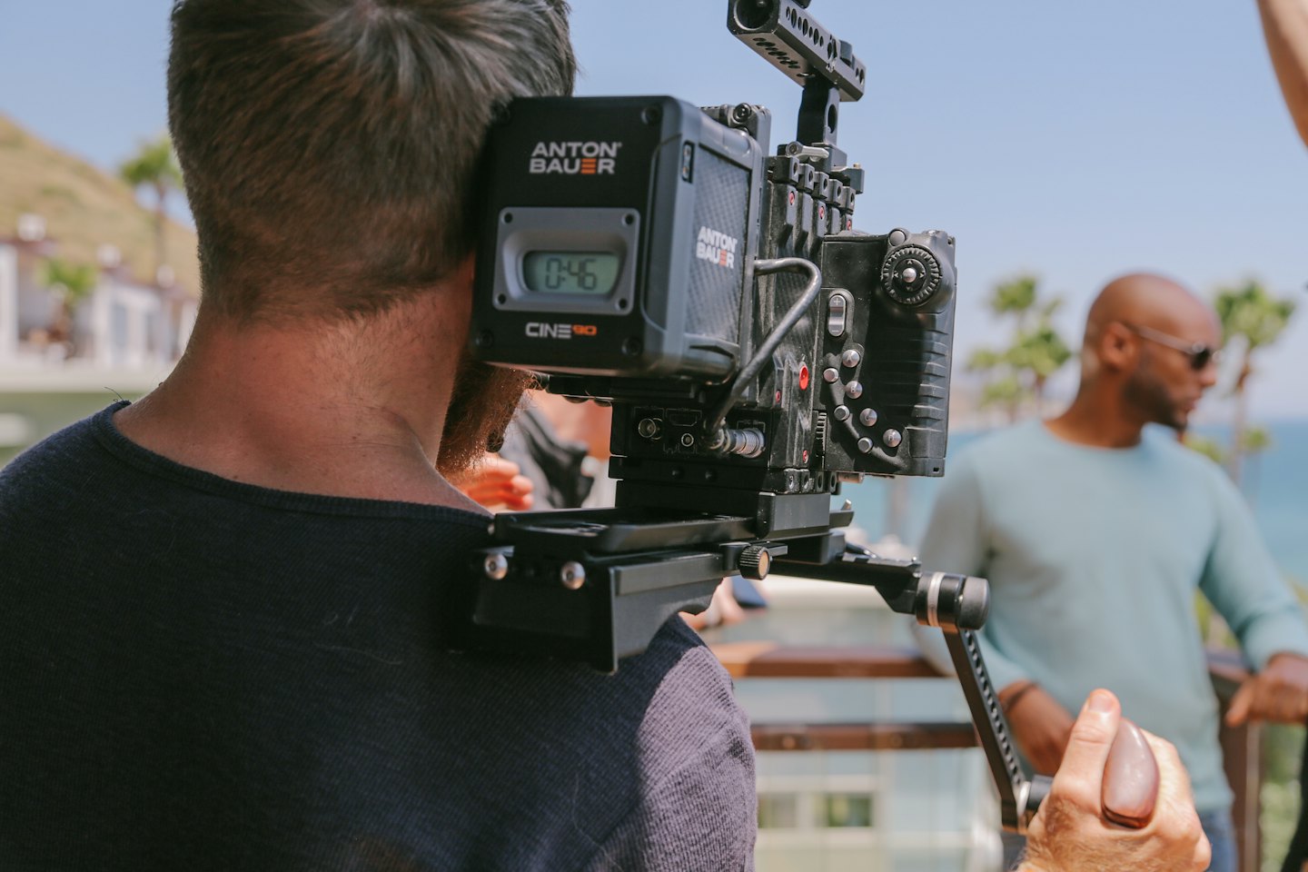 Cameraman films with a professional video camera rig outdoors.